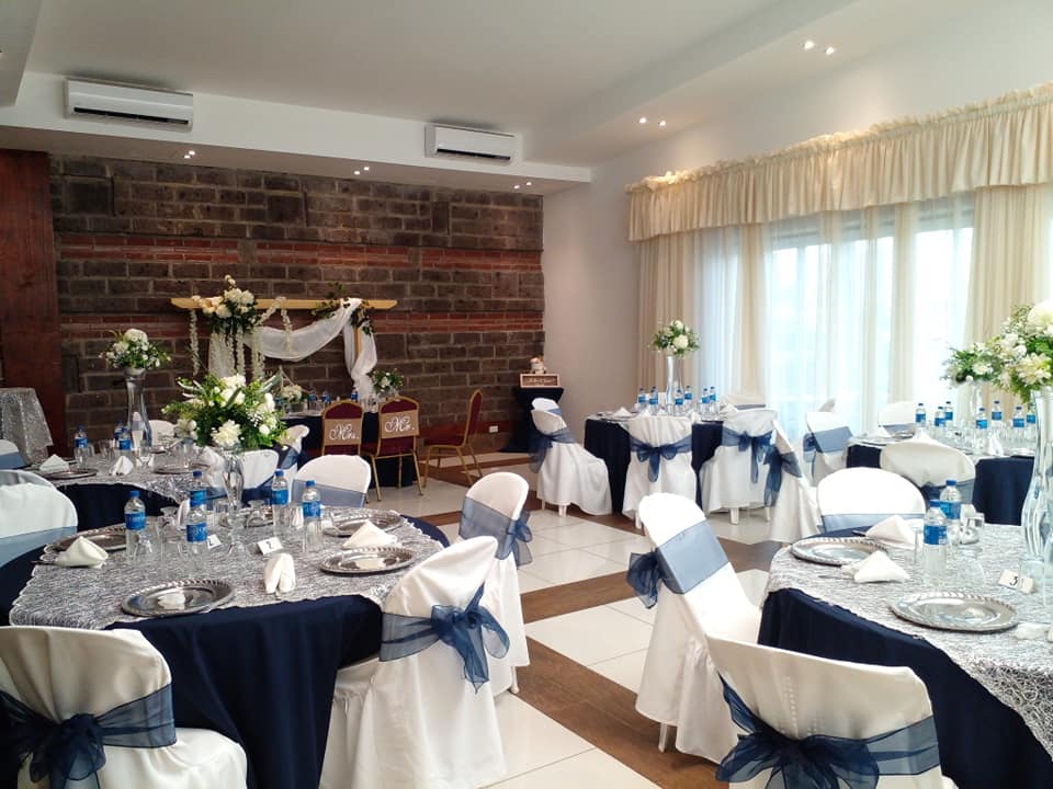 Salón de bodas montado en azul marino y plata con sillas para los novios