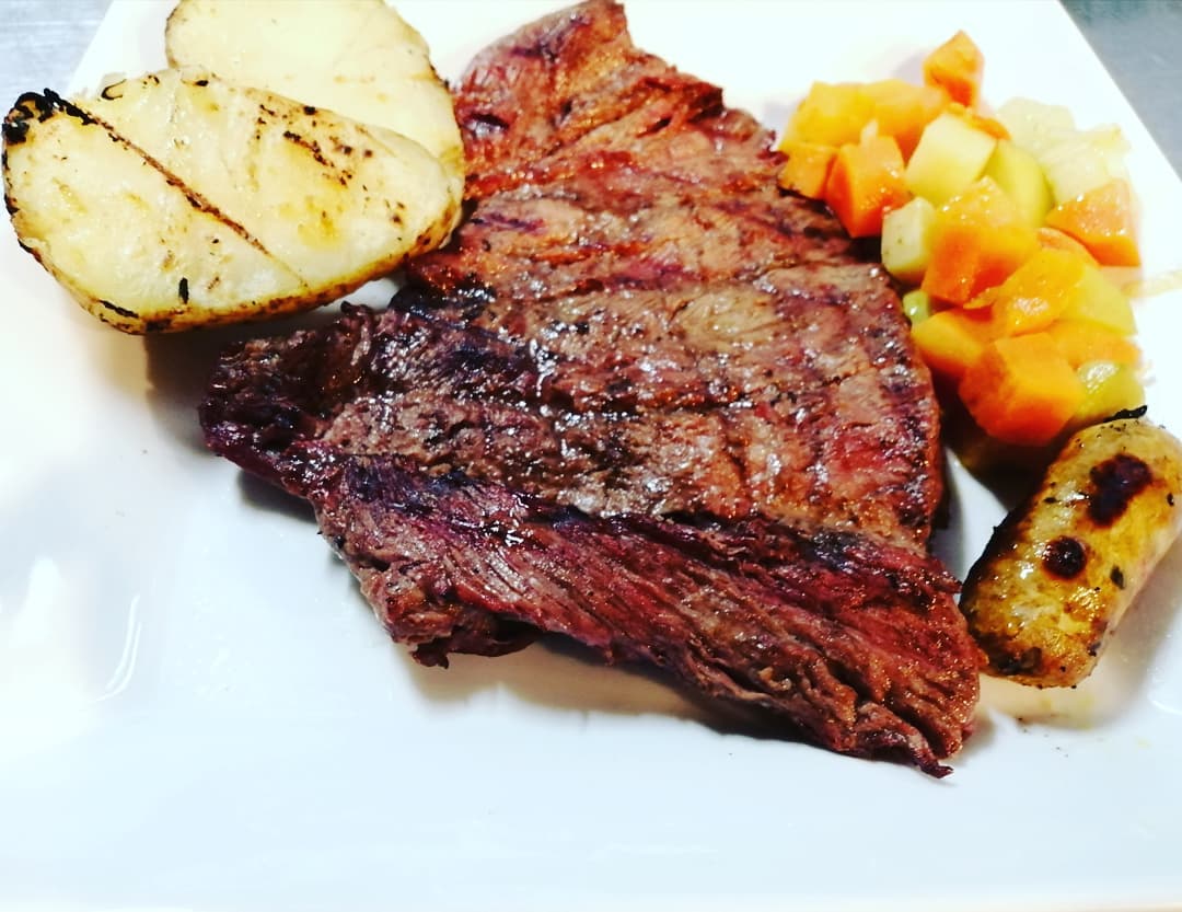 Churrasco a la parrilla con papas y vegetales, servido en El Patio