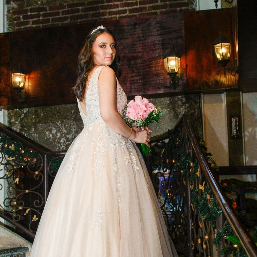 Quinceañera posando en las escaleras de El Patio con su ramo