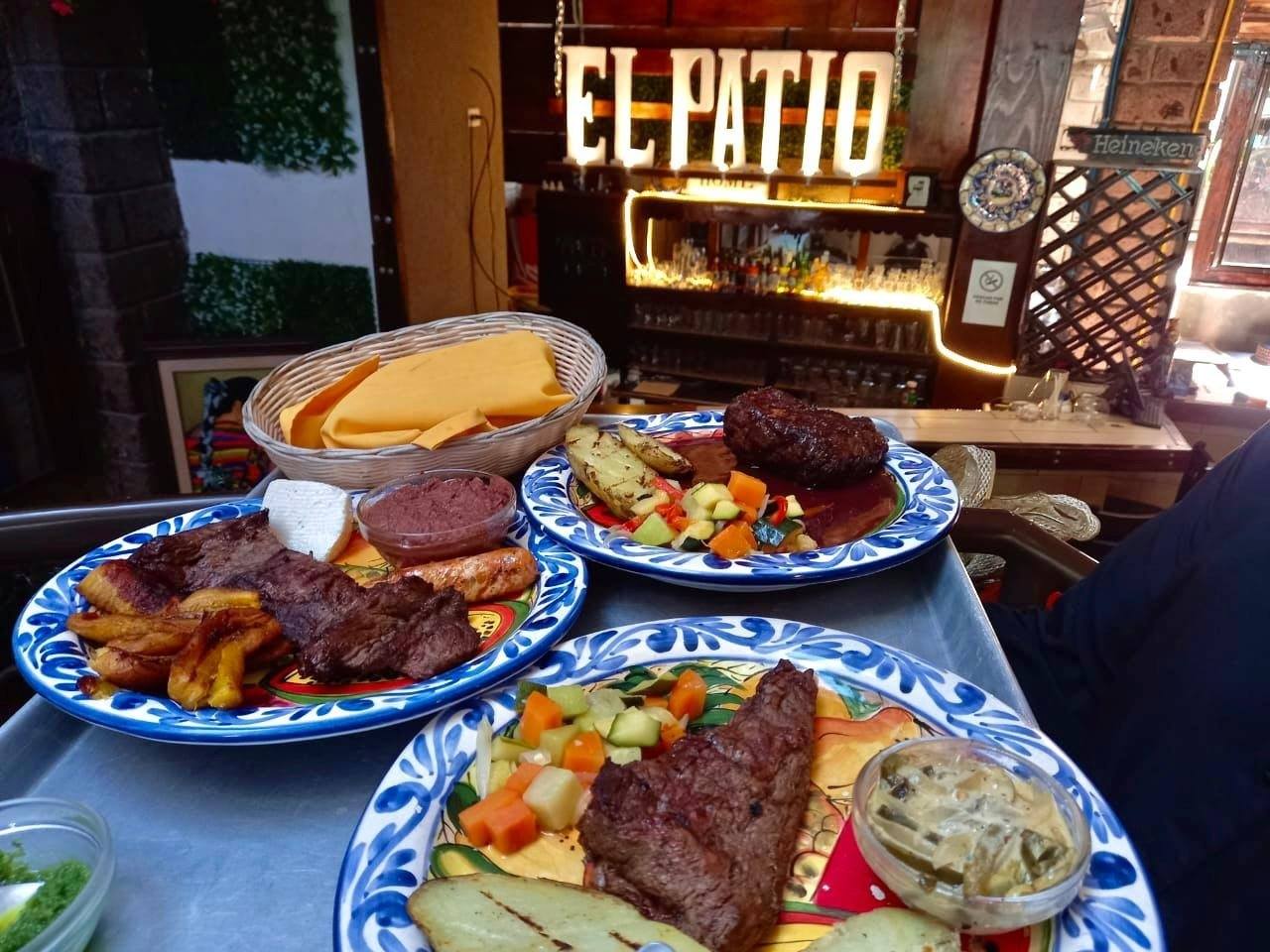 Interior del restaurante El Patio con platillos a la parrilla y el letrero luminoso del local