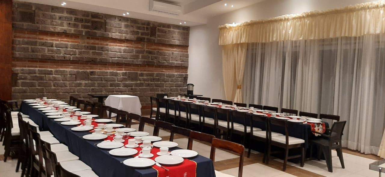 Salón con pared de ladrillo expuesto montado con mesas largas para banquete